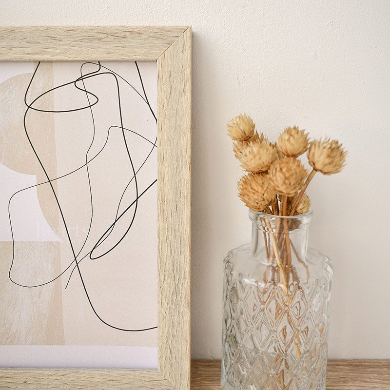 Close up of picture frame next to clear vase with yellow plant inside