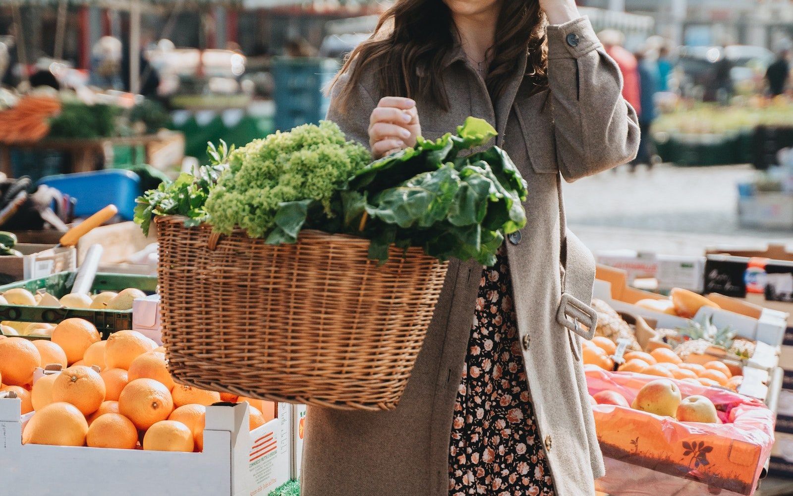 woman at local farmers market carrying a basket full of vegetables